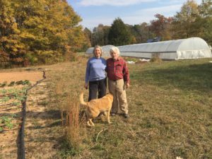 Couple standing outside on their farm with their large dog